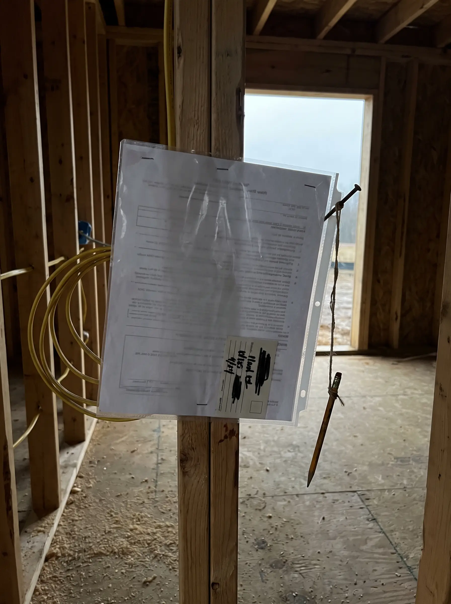 Permit papers in a plastic sleeve stapled to a stud inside a framed house